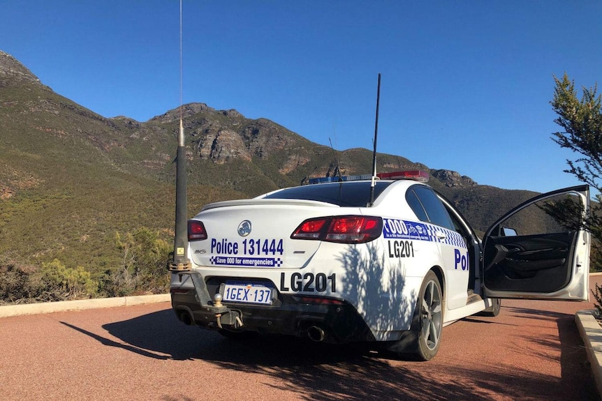 A police car sitting in a car park with Bluff Knoll in the background.