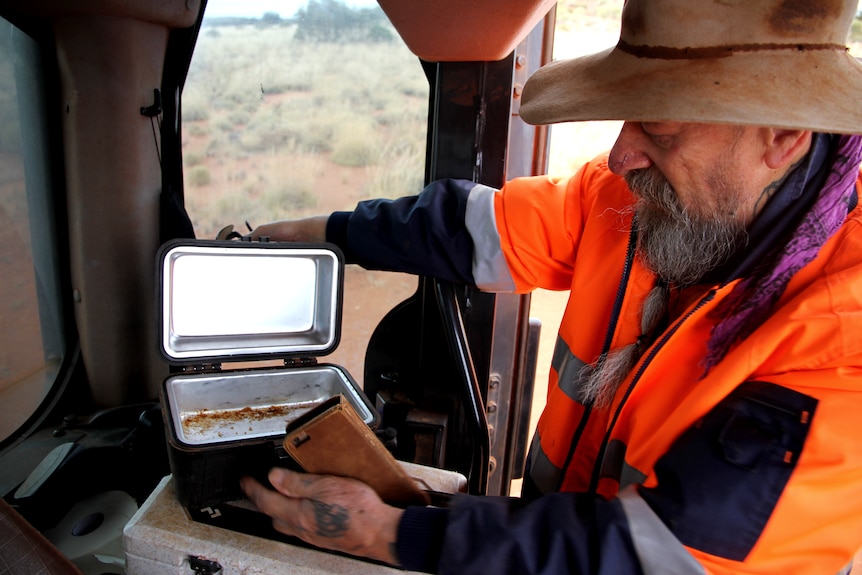 A man opening a pie warmer. 