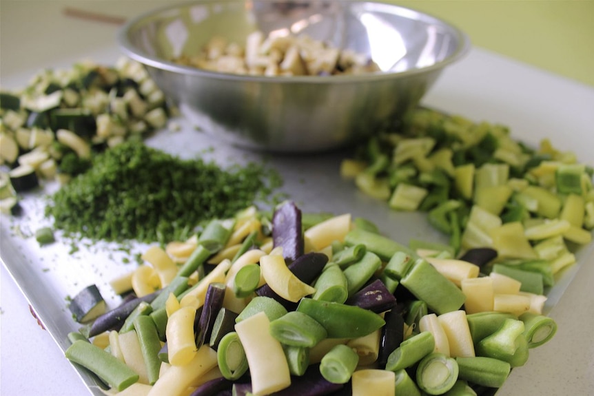 Chopped beans, peppers, zucchini, eggplant and parsley on a board