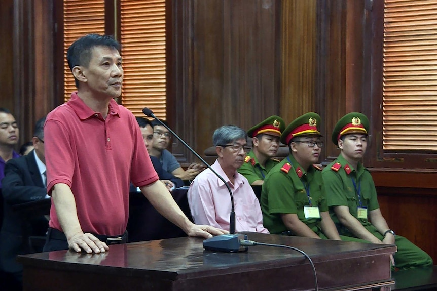 Michael Nguyen is standing on trial, in front of a microphone.