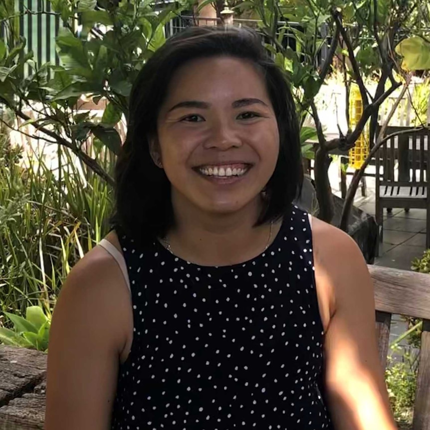 A woman smiles while sitting at a picnic table