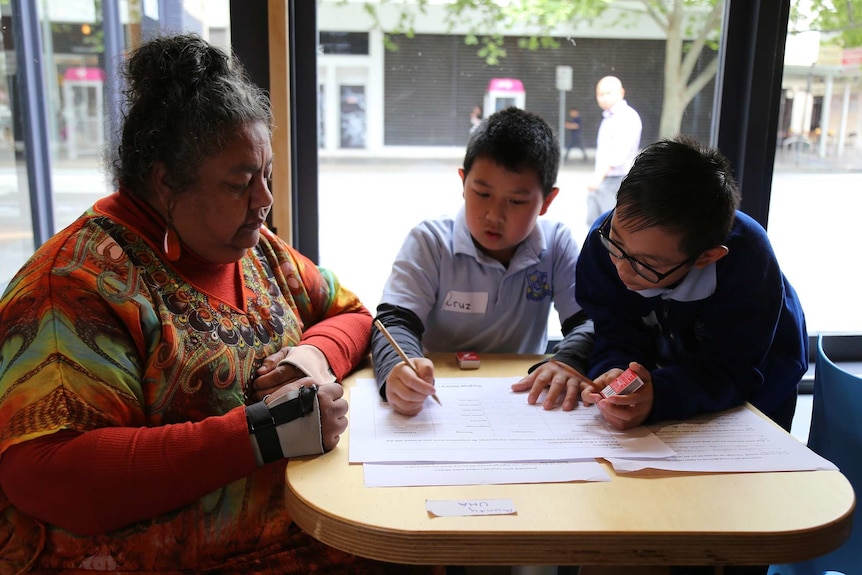 Two children and an adult sit at a table