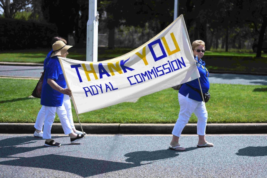 Two women hold a banner saying "Thanks you royal commission.