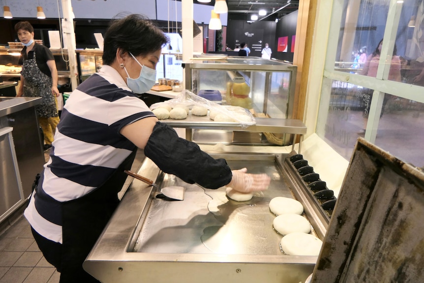 A woman cooks in a shop.