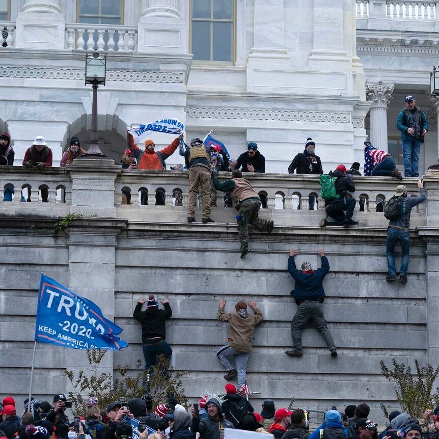 Trump supporters climb a stone wall during a riot at the US Capitol.