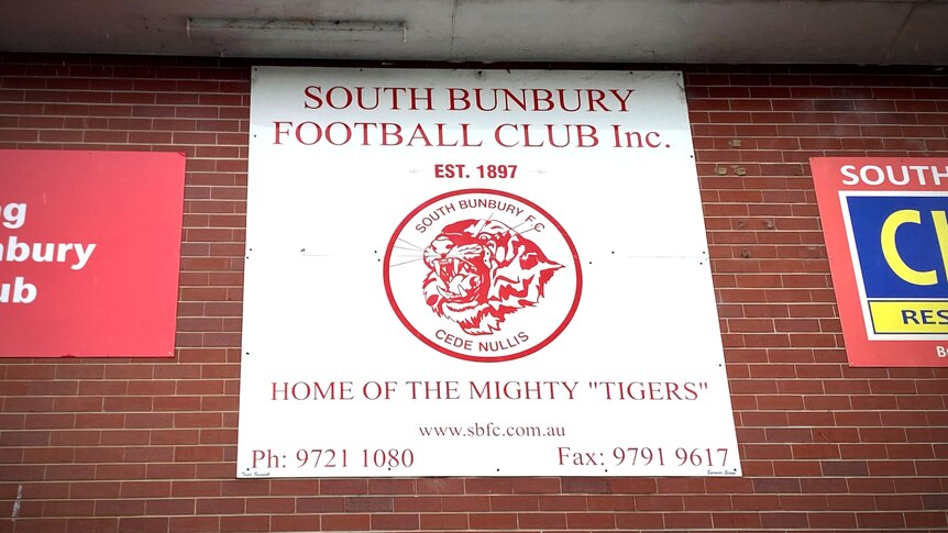 A football club logo hangs on a sign on a brick wall