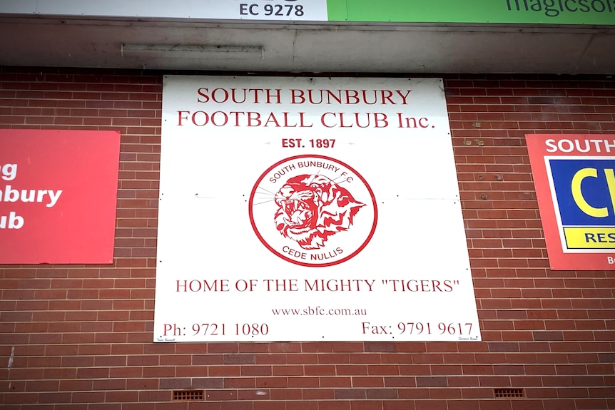 A football club logo hangs on a sign on a brick wall