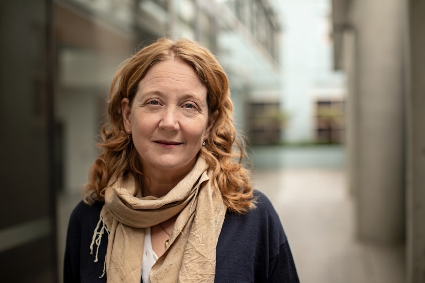 Dr Ruth Peters wearing beige scarf, standing in front of building.