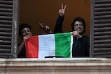 Two young Italians giving peace signs while holding up their flag
