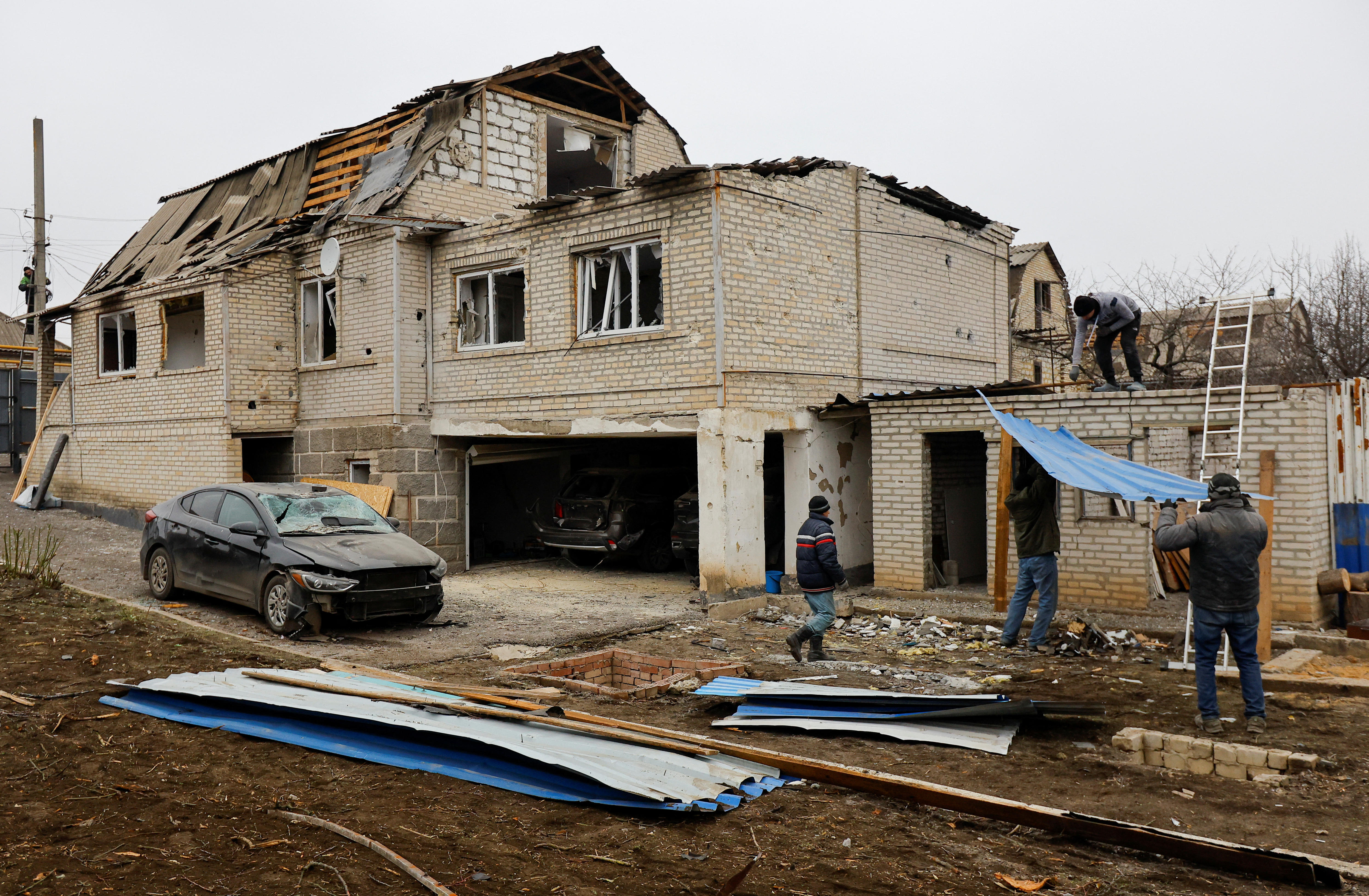 People standing around a house with a destroyed roof. 