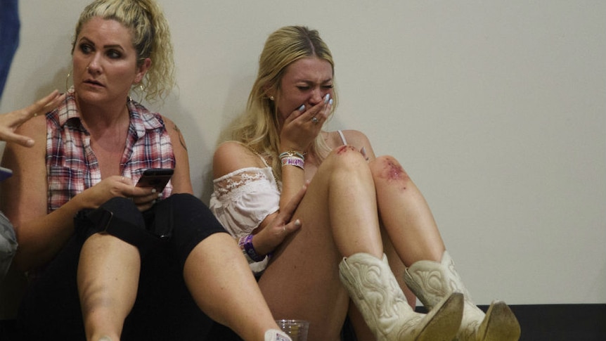 A woman sits crying with blood on her knee.