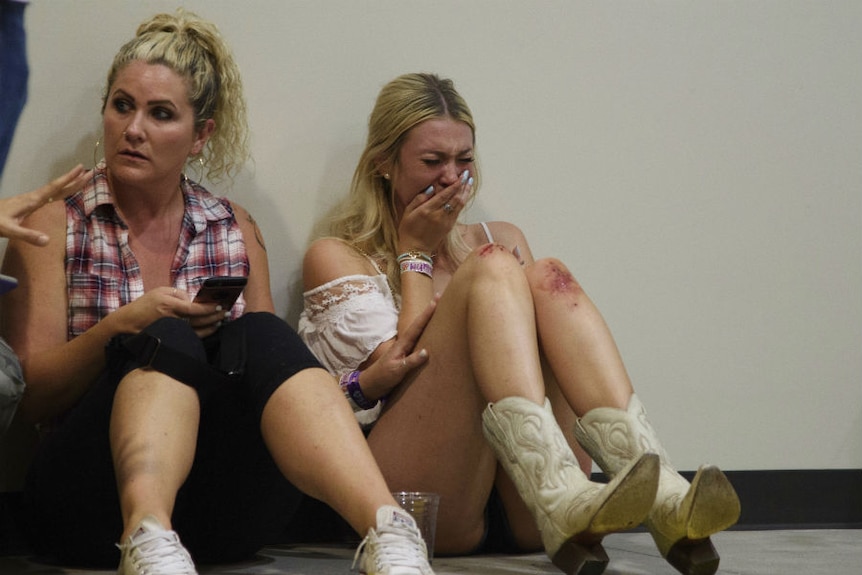 A woman sits crying with blood on her knee.