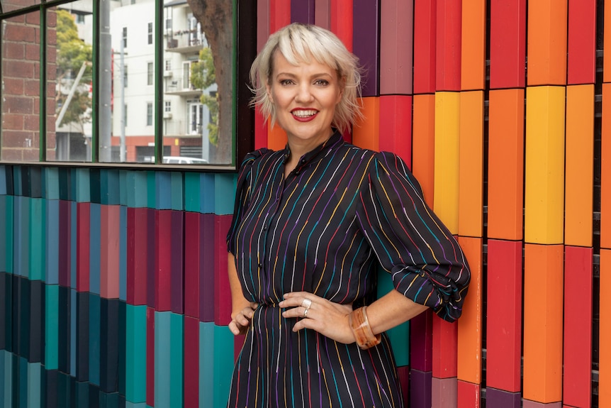 A portrait of ABC presenter Jacinta Parsons against a bright, colourful backdrop