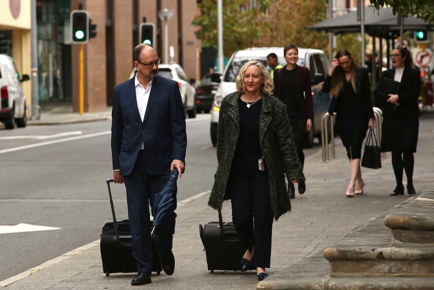 Defence lawyer Paul Yovich SC arrives at court, he wears a suit, no tie and wheels a suitcase.