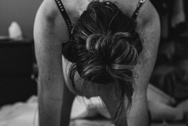 black and white photo of a woman wearing a black bra on her hands and knees in labour