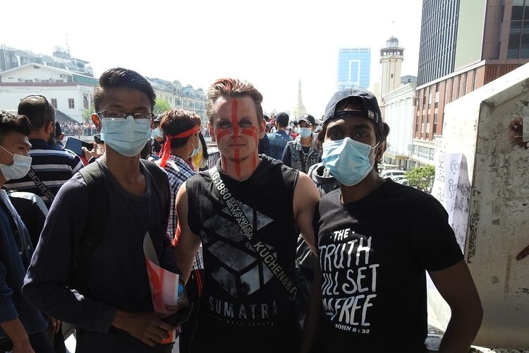 Australian Mitchell Schmidt with face paint, in between two men with face masks.