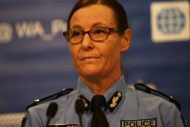 A policewoman with her hair tied back, wearing glasses, appears at a media conference.