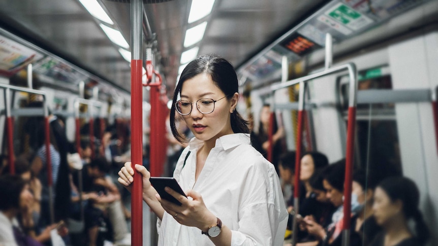 A woman on the subway holds a smartphone.