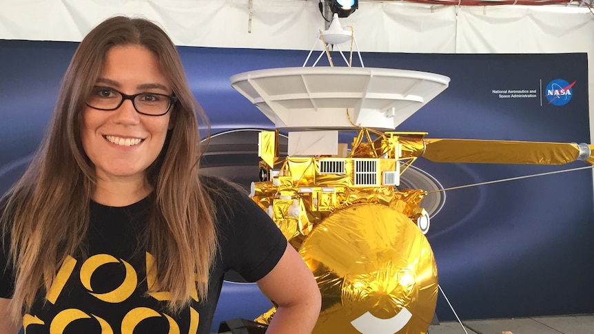 Ashley Schoenfeld stands in front of a 1:8 scale model of the Cassini-Huygens spacecraft