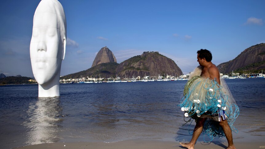 A fisherman looks at a large sculpture in the water at Botafogo Beach.