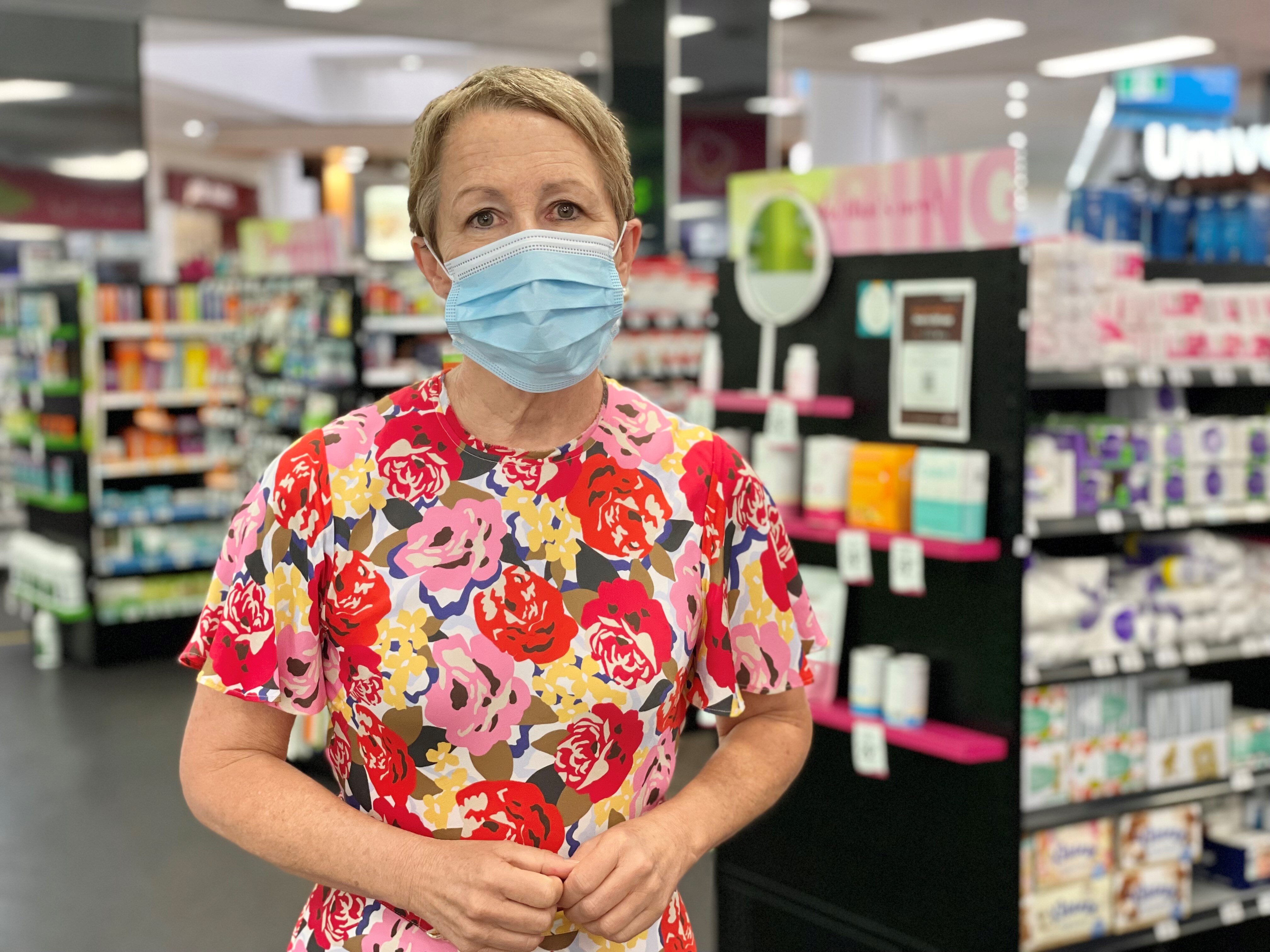 Profile photo of a woman in a shop, wearing a mask.