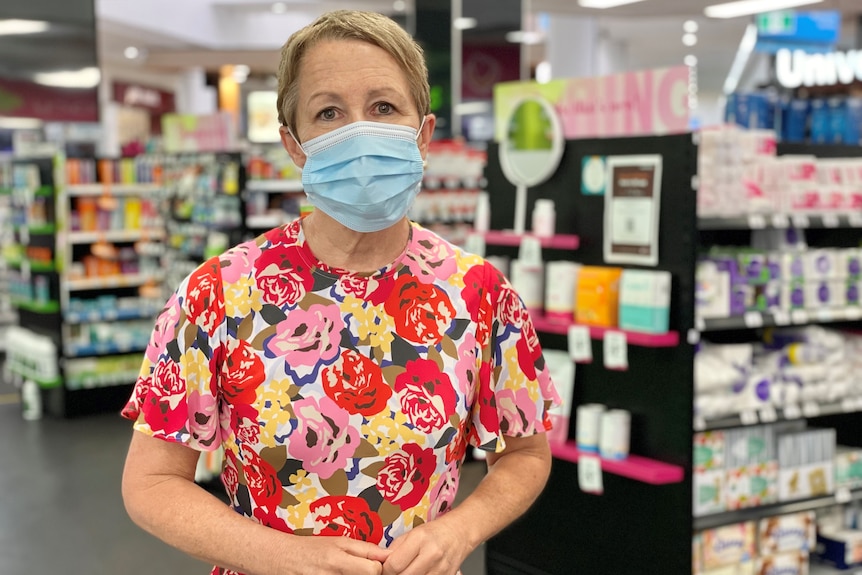 Profile photo of a woman in a shop, wearing a mask.