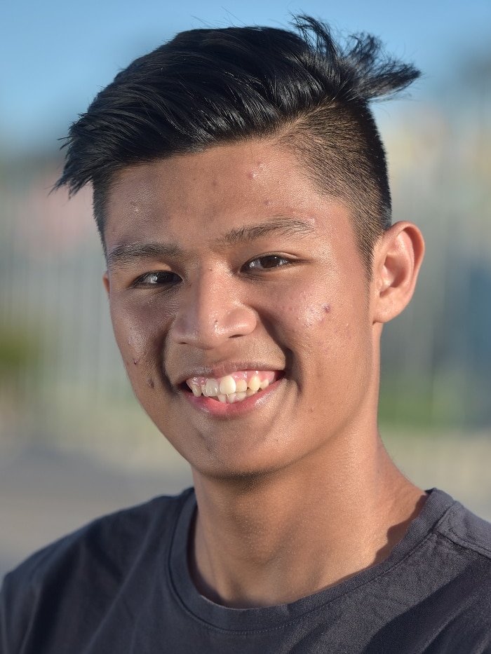 A portrait picture of a young man with black hair and a dark grey t-shirt, smiling.