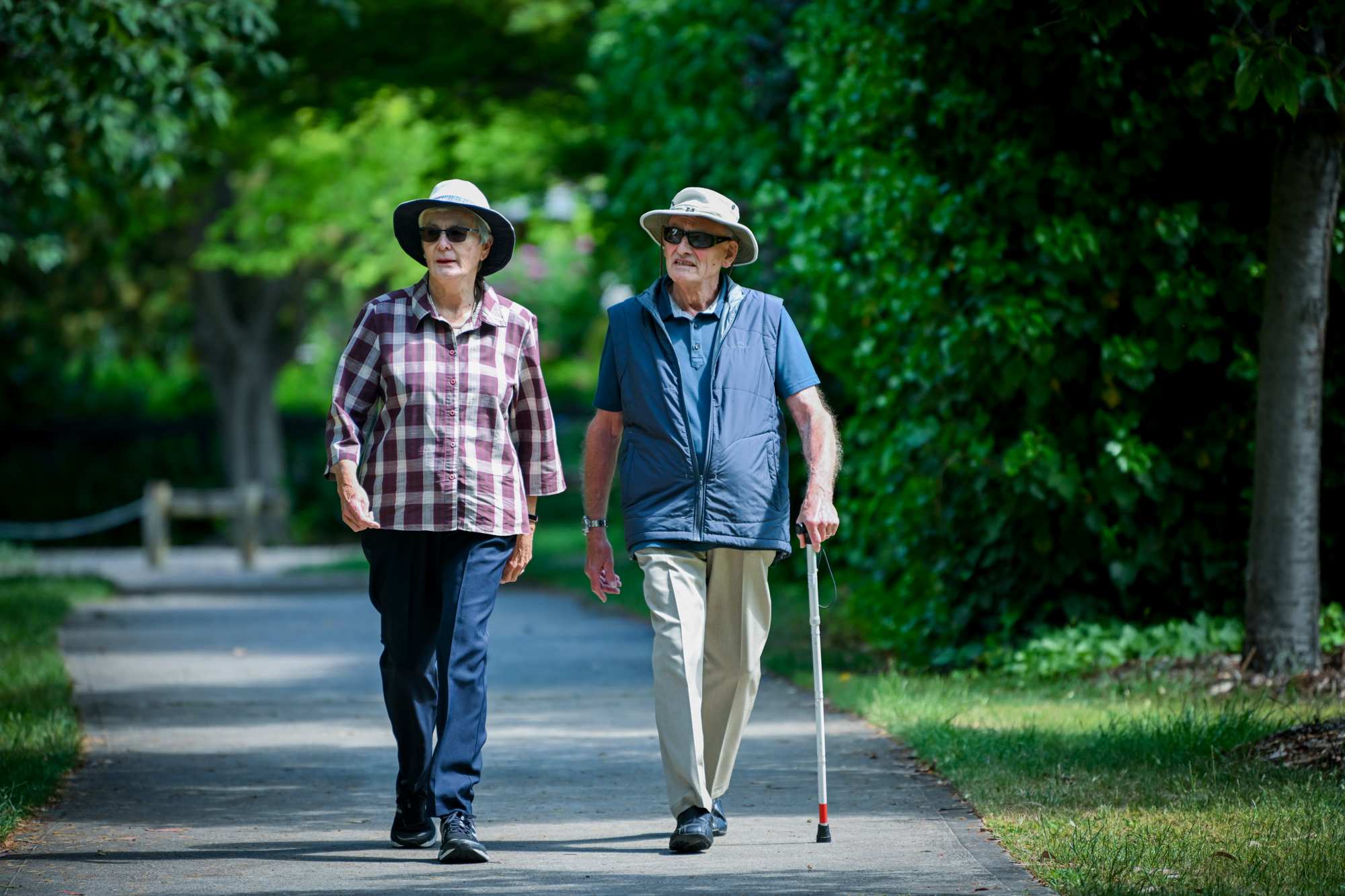 Two elderly walking people walking down the street.