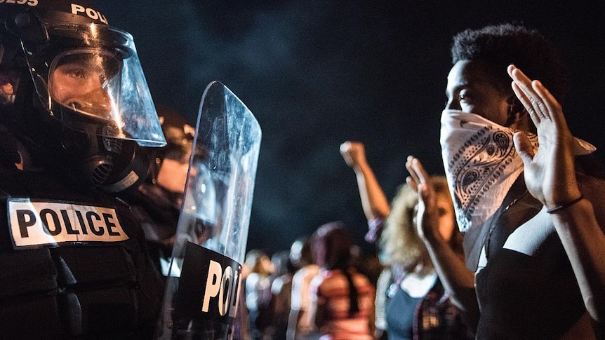 Armed police with shields face off with protestors in the US.