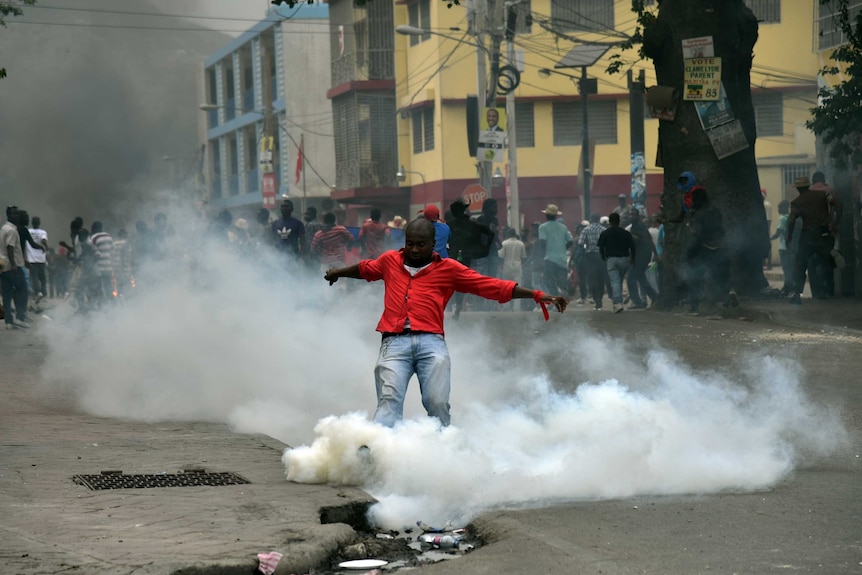 A man kicks a tear gas canister in Port-au-Prince, Haiti