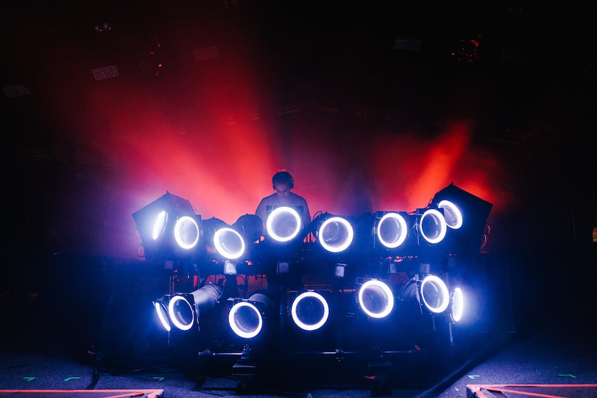 Four Tet performs behind a large bank of spinning blue lights in darkness at Golden Plains festival 2023