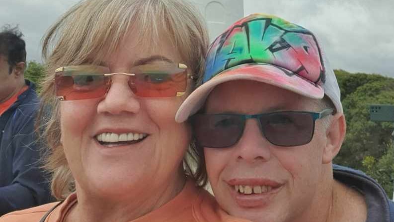 A lady and her son smile in front of a lighthouse.