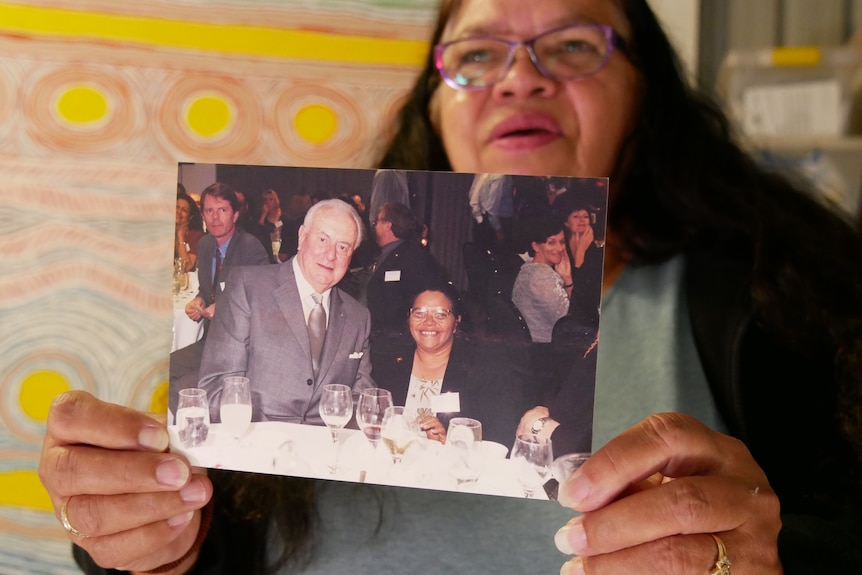 A woman holds a photo up
