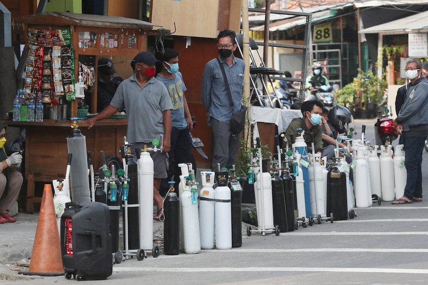 People queue with oxygen tanks on the street in Indonesia
