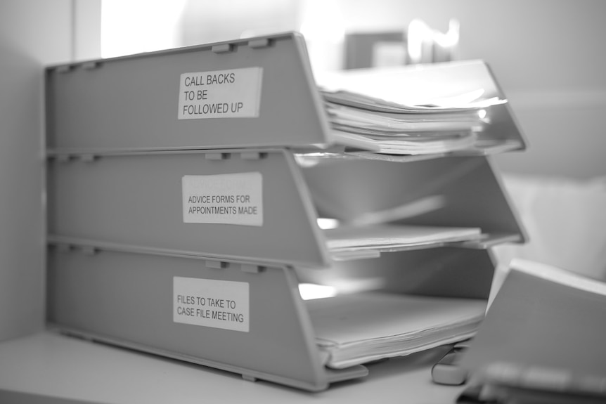 Three desk files stacked on top of each containing paperwork from SA Women's Legal Service