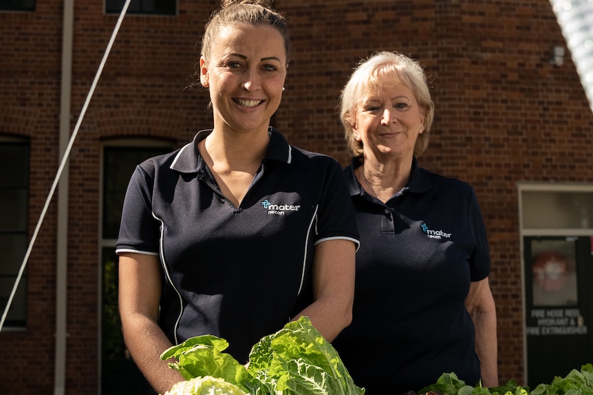 Two ladies standing near a garden.