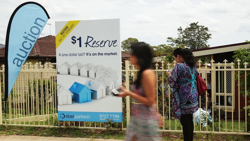 Two women walk past a property for sale in Blacktown, NSW