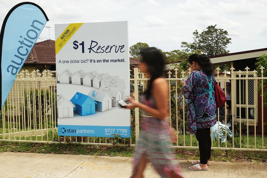 Two women walk past a property for sale in Blacktown, NSW