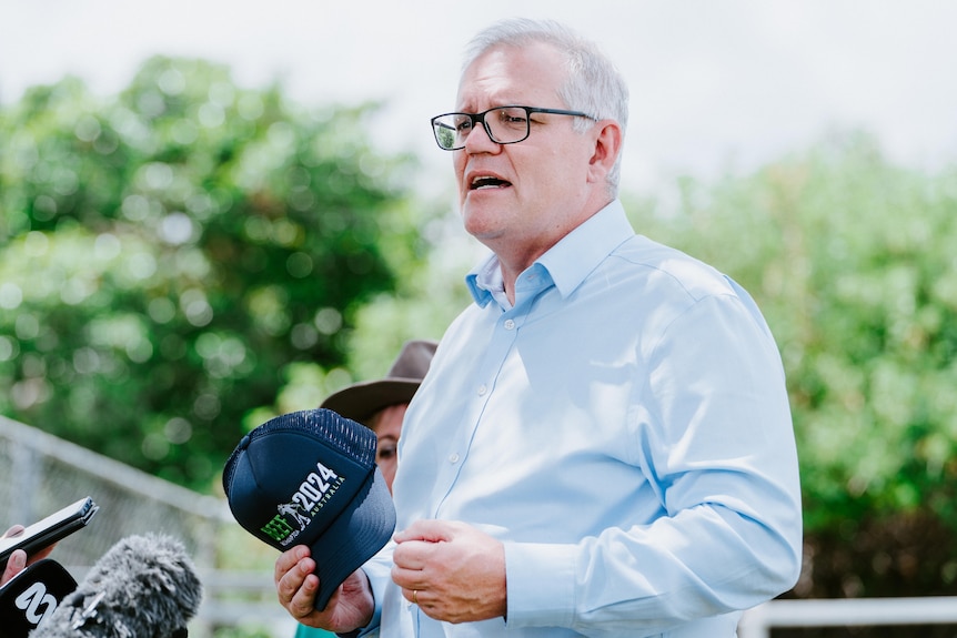 Scott Morrison holds a cap in his hand while speaking at a press conference