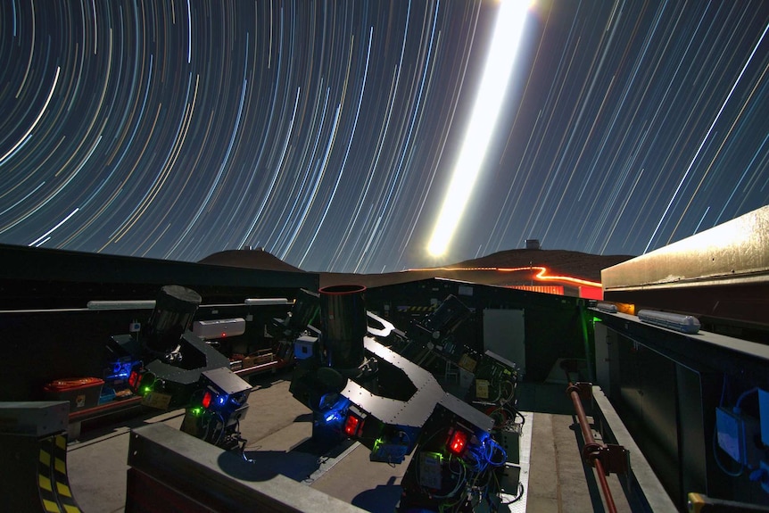 Stars appear as light in concentric rings in the sky above a telescope.
