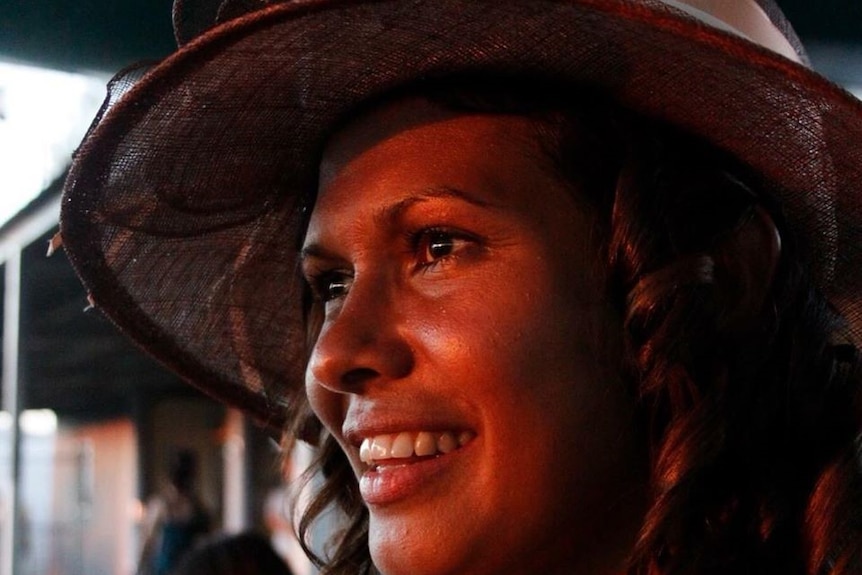 A woman of a hat smiles as she looks into the distance, she talks to her kids about First Nations people and land through travel