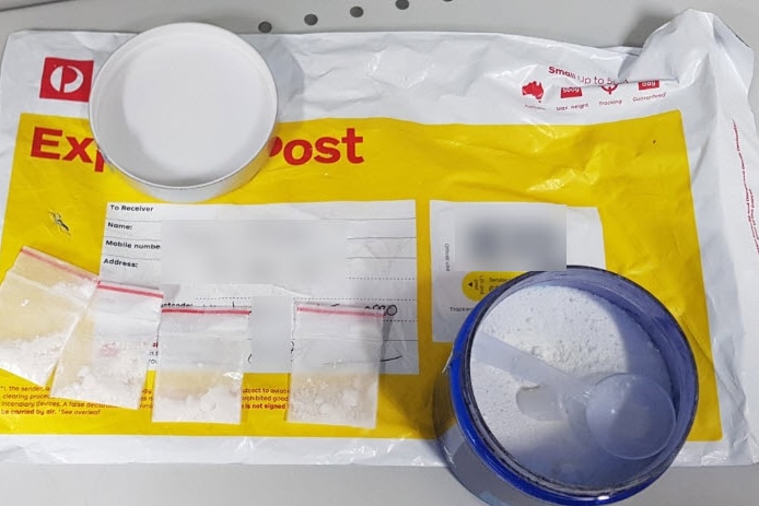 Cocaine sitting in packets and a container on top of an Australia Post parcel.
