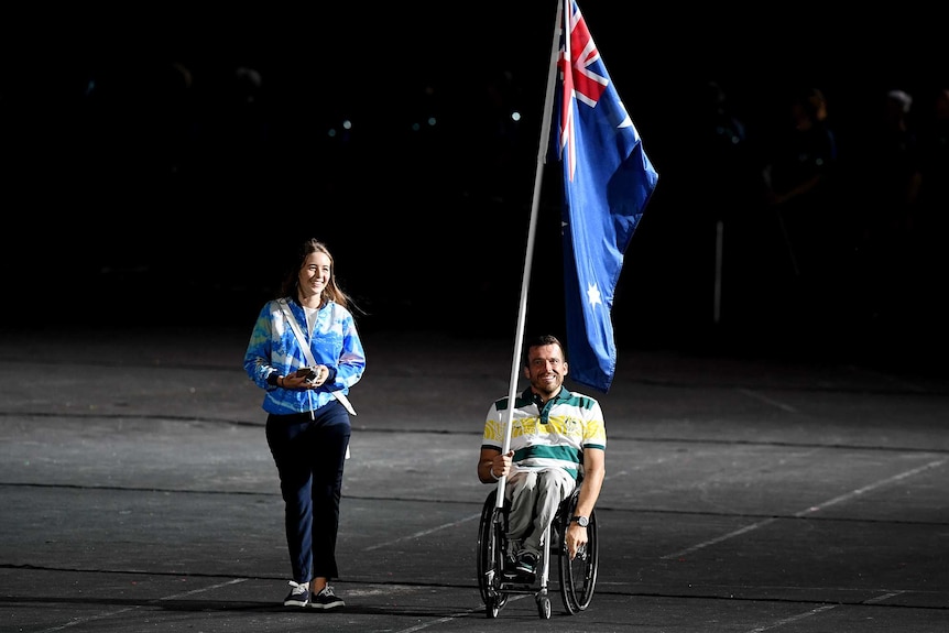 Flagbearer Kurt Fearnley enters the stadium before the start of the closing ceremony of the XXI Commonwealth Games
