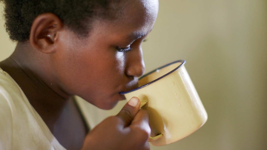 A child with TB drinks from a mug.