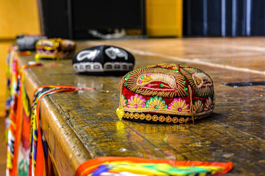 A variety of doppas, a type of Uyghur skullcap, are arranged at the end of a stage. They are colourful and embroidered.