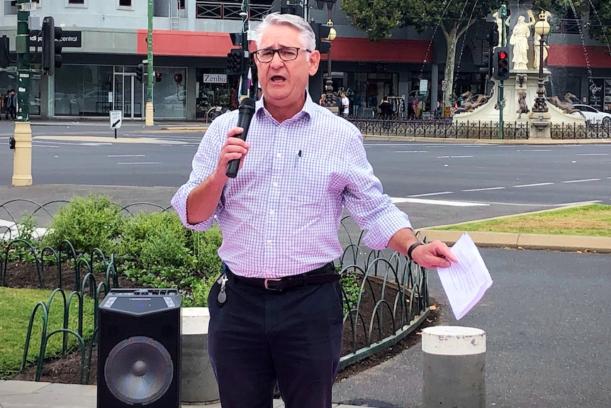 a man with grey hair speaks into a microphone