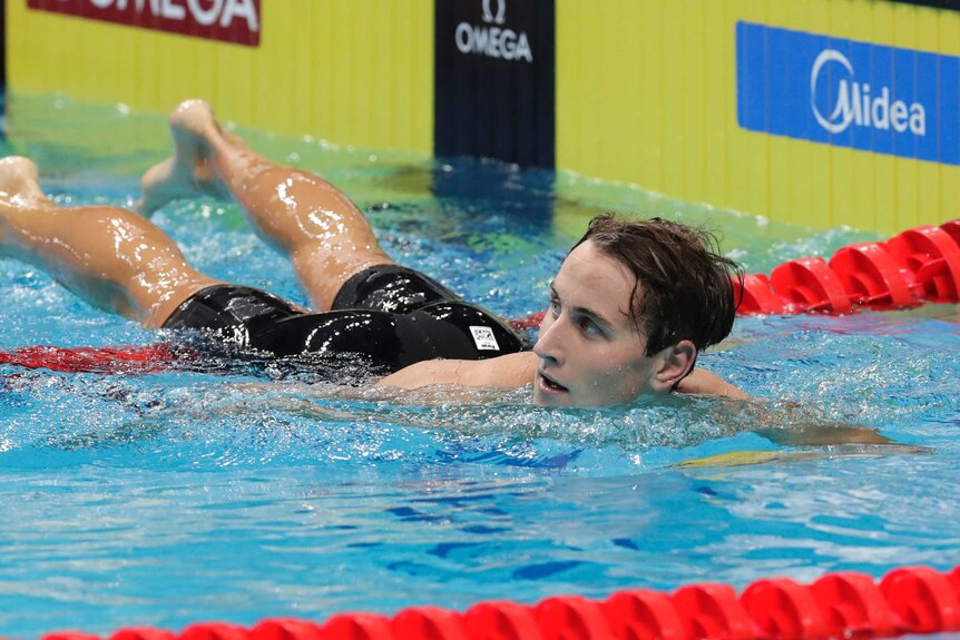 Cameron McEvoy looks away and slides over the lane ropes in a pool.