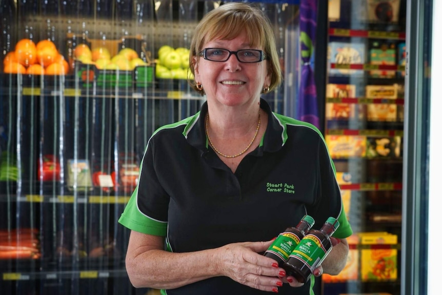 Faye Hartley stands in front of fruit at a grocery store