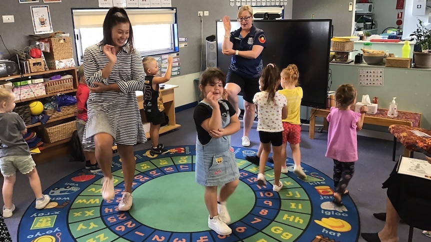 Two teachers and students dancing in a circle. 