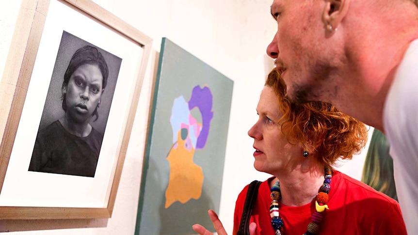 a woman looking at a charcoal drawing